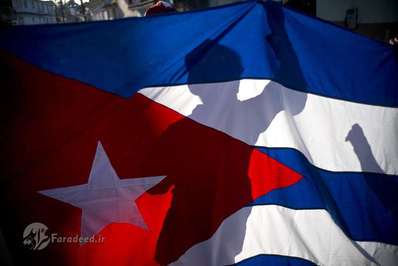  یک کودک پرچم کوبا را در مراسم ۵۹ سالگرد ورود فیدل کاسترو به ارتش شورشی در دست گرفته است، هاوانا، کوبا.