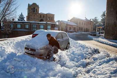 مردی که برای پاک کردن برف از روی ماشین، از یک بیل استفاده می‌کند، اسپانیا.