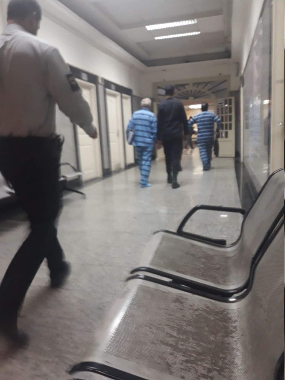 حسین هدایتی با دستبند و ماسک در راهرو دادگاه کیفری تهران