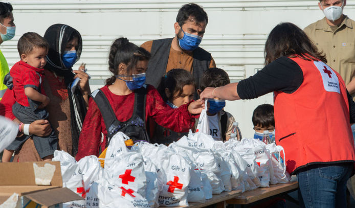 نمایندگان صلیب سرخ در میان پناهپویان افغان در پایگاه هوایی رامشتاین در آلمان کمک های انسانی توزیع می کنند
